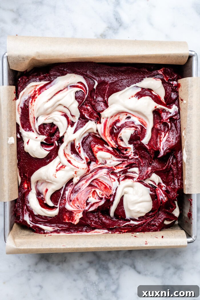 Unbaked vegan red velvet brownies with cheesecake swirl, ready for the oven.