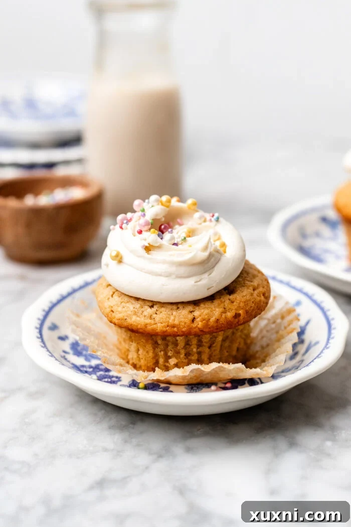 cupcake liner peeled off of a perfectly baked vegan vanilla cupcake, highlighting its moist texture
