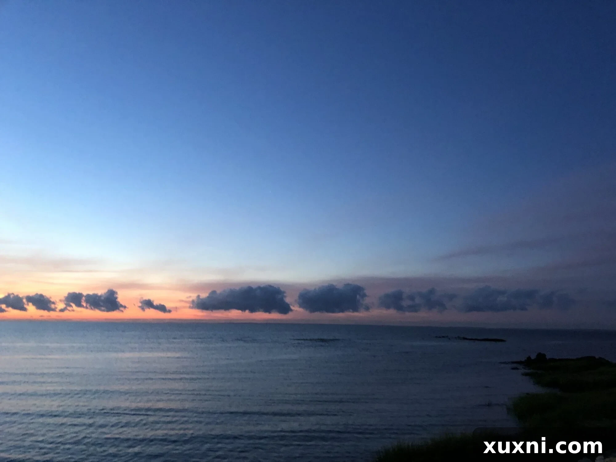 Serene sunrise painting the ocean in hues of orange and pink, a tranquil start to the day.