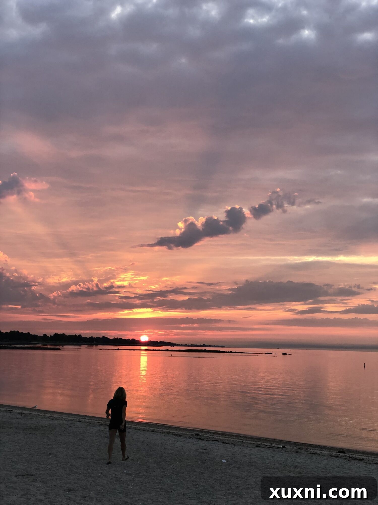 A vibrant pink sky during sunrise, casting a beautiful glow over the tranquil ocean surface.
