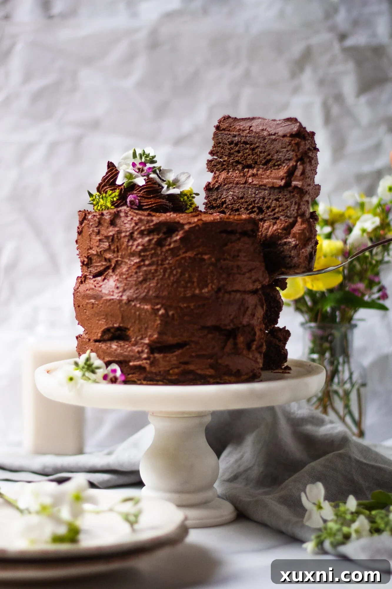 A delicious slice of ultra-rich and decadent chocolate zucchini cake, taken from a full cake. This undetectably healthy dessert is completely vegan, dairy-free, Paleo, and gluten-free, promising a moist and chocolatey slice of heaven without a single speck of zucchini visible. Perfect for kids, families, and all chocolate lovers!