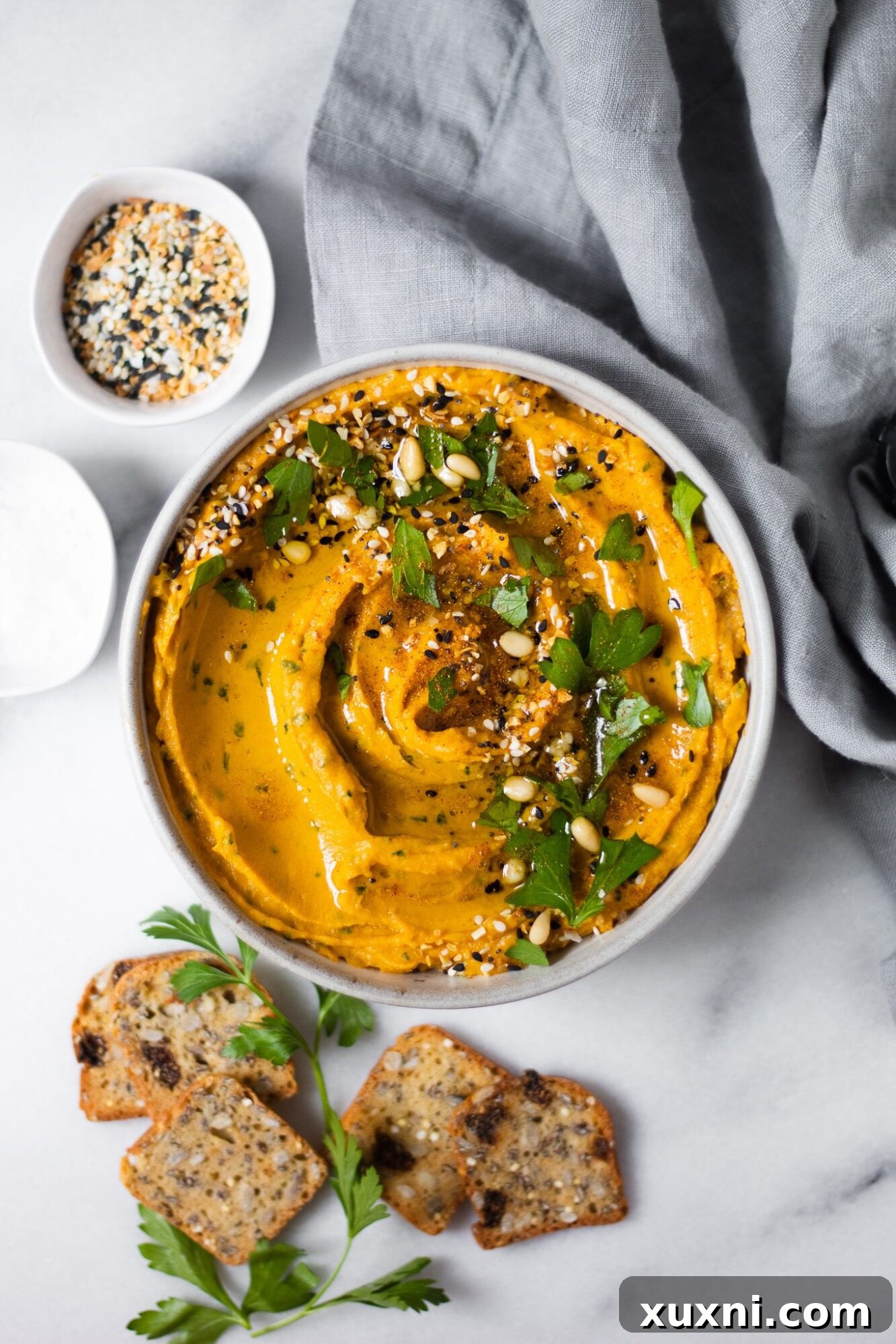 Sweet potato hummus served with crackers on a wooden board, ready to be enjoyed.