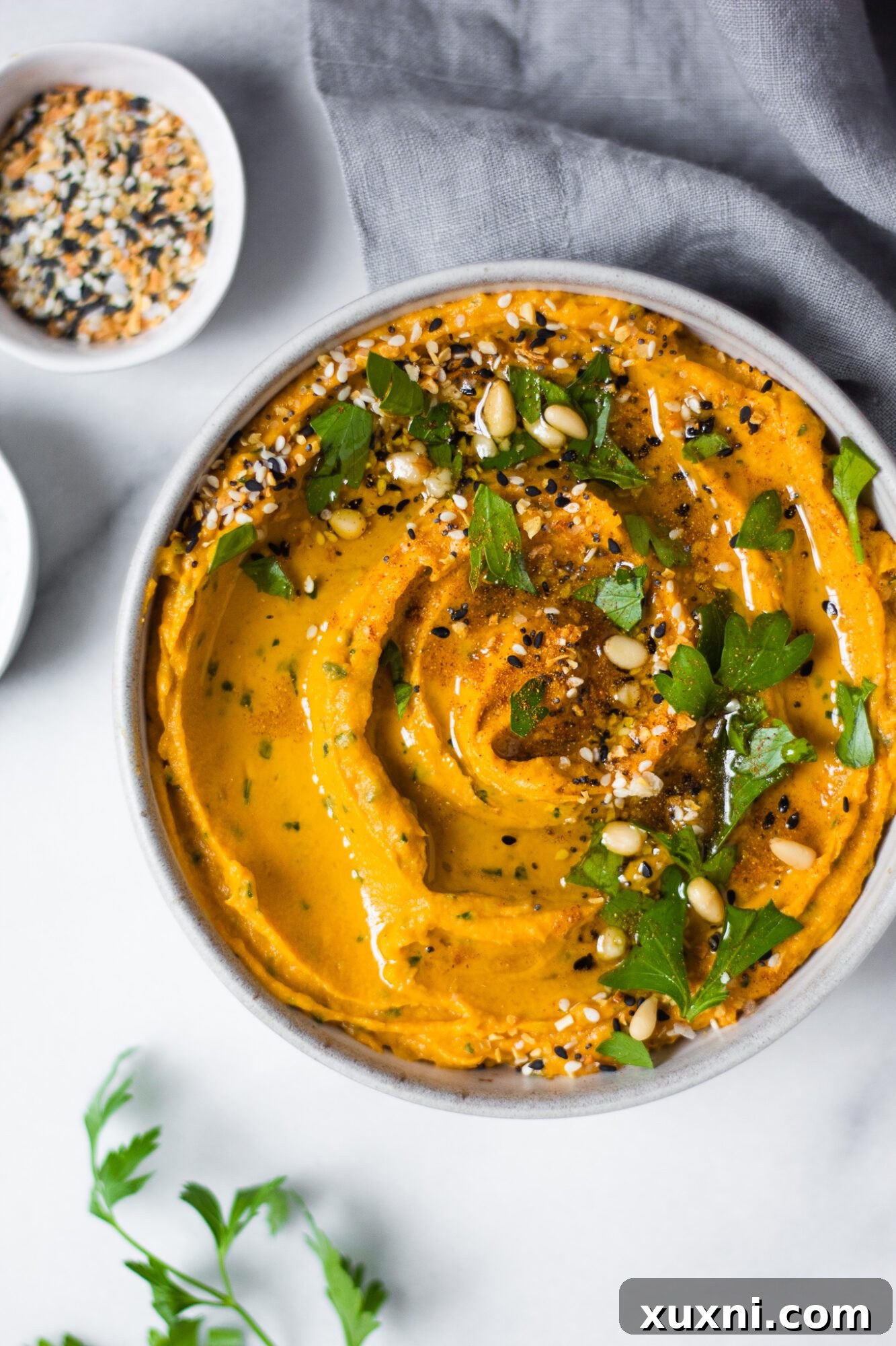 Healthy sweet potato hummus garnished with a sprinkle of paprika and fresh parsley.