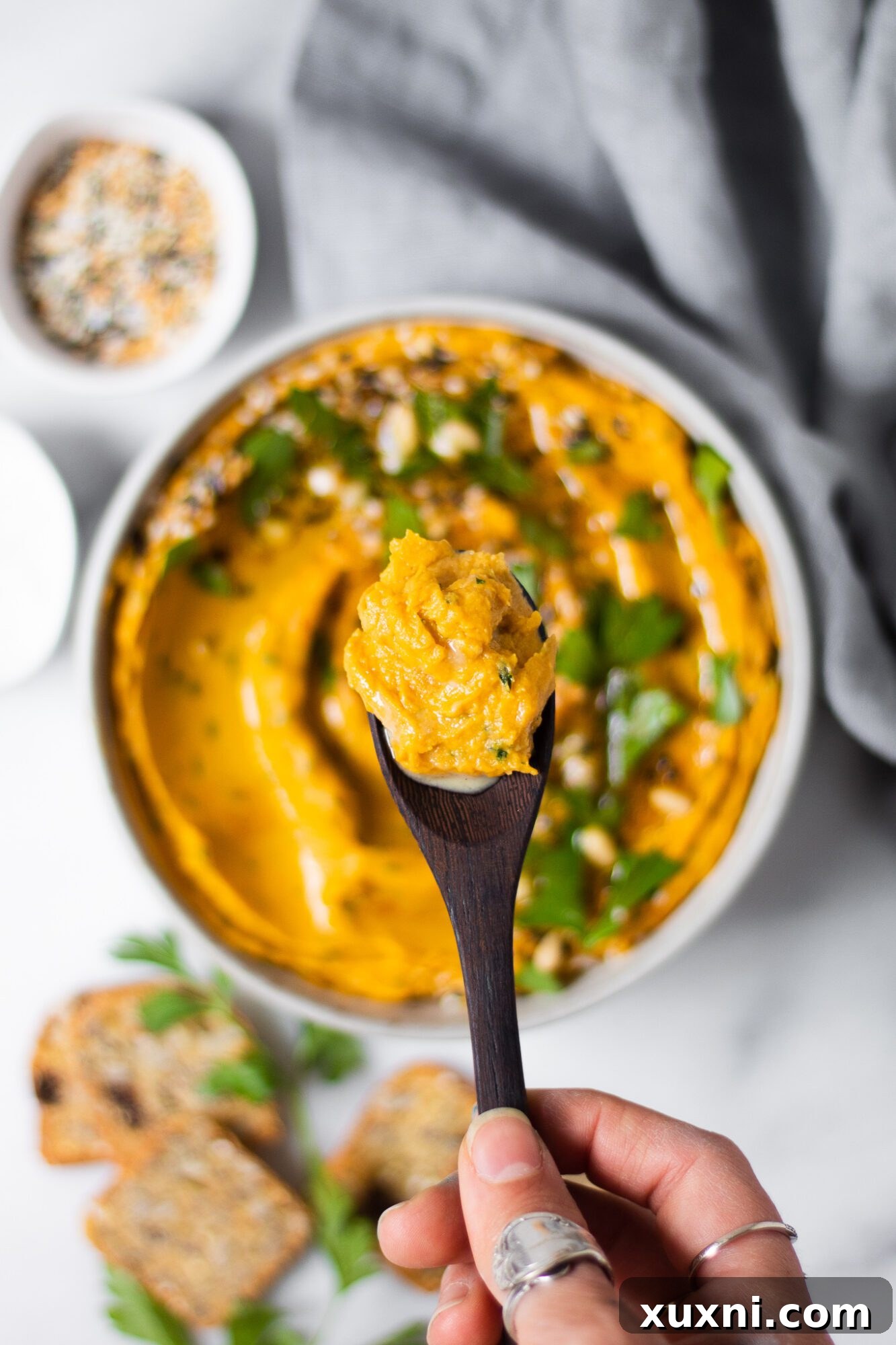 Spoonful of creamy sweet potato hummus being lifted from a bowl.