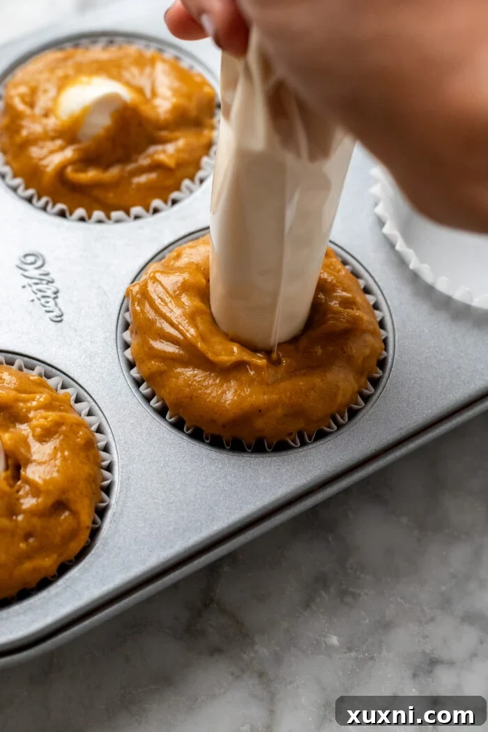 filling the pumpkin muffins with cream cheese