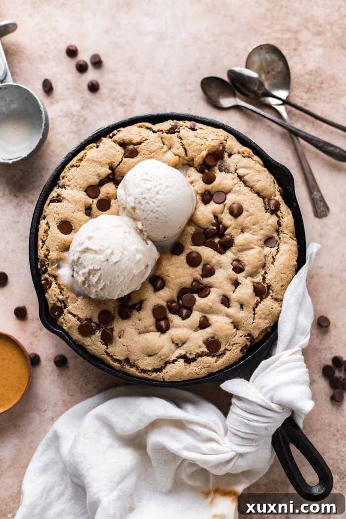 Baked vegan skillet cookie garnished with melting ice cream