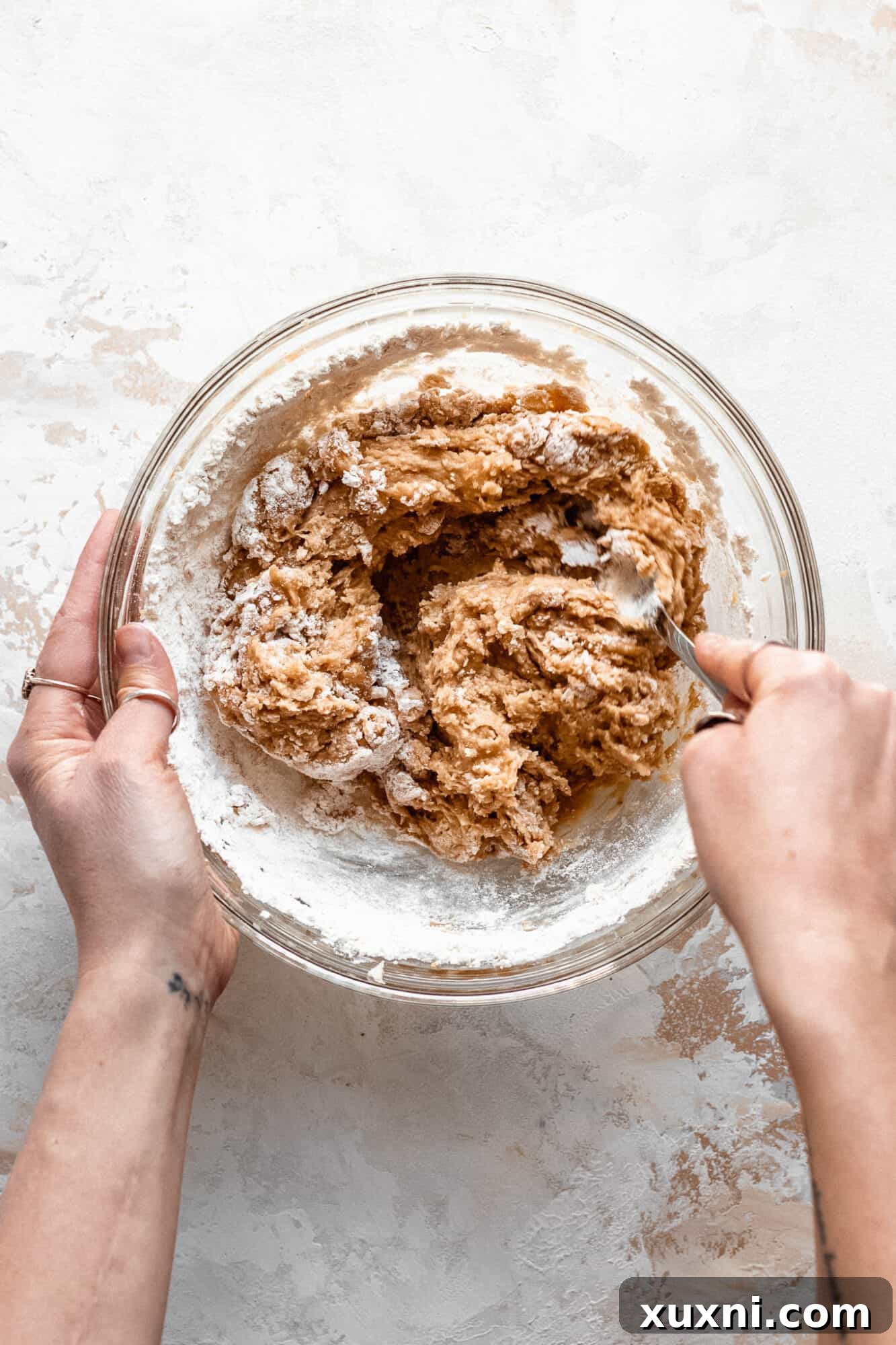 Hand folding chocolate chips into peanut butter cookie batter