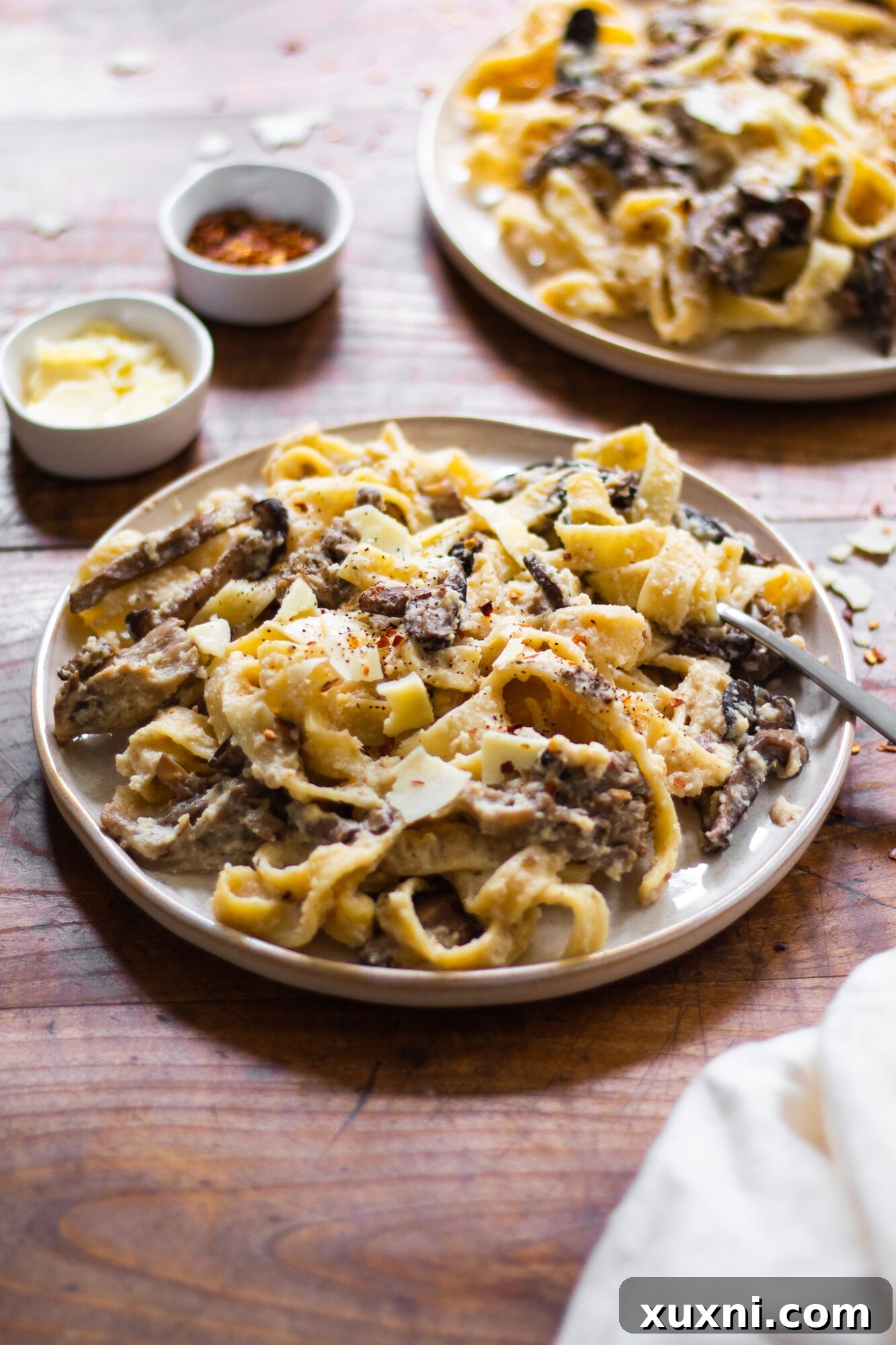 Guilt-Free Fettuccine Alfredo 2 Plates of creamy vegan cauliflower Alfredo with fettuccine pasta, garnished with fresh herbs, showcasing a delicious and healthy meal option.