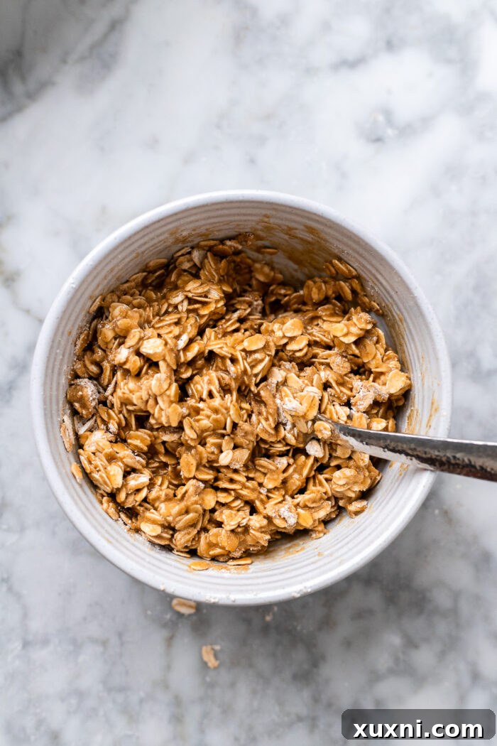Quick Vegan Apple Crisp Naturally Sweetened 8 Ingredients for the oat crisp topping, including oats, flour, and spices, being mixed in a bowl.