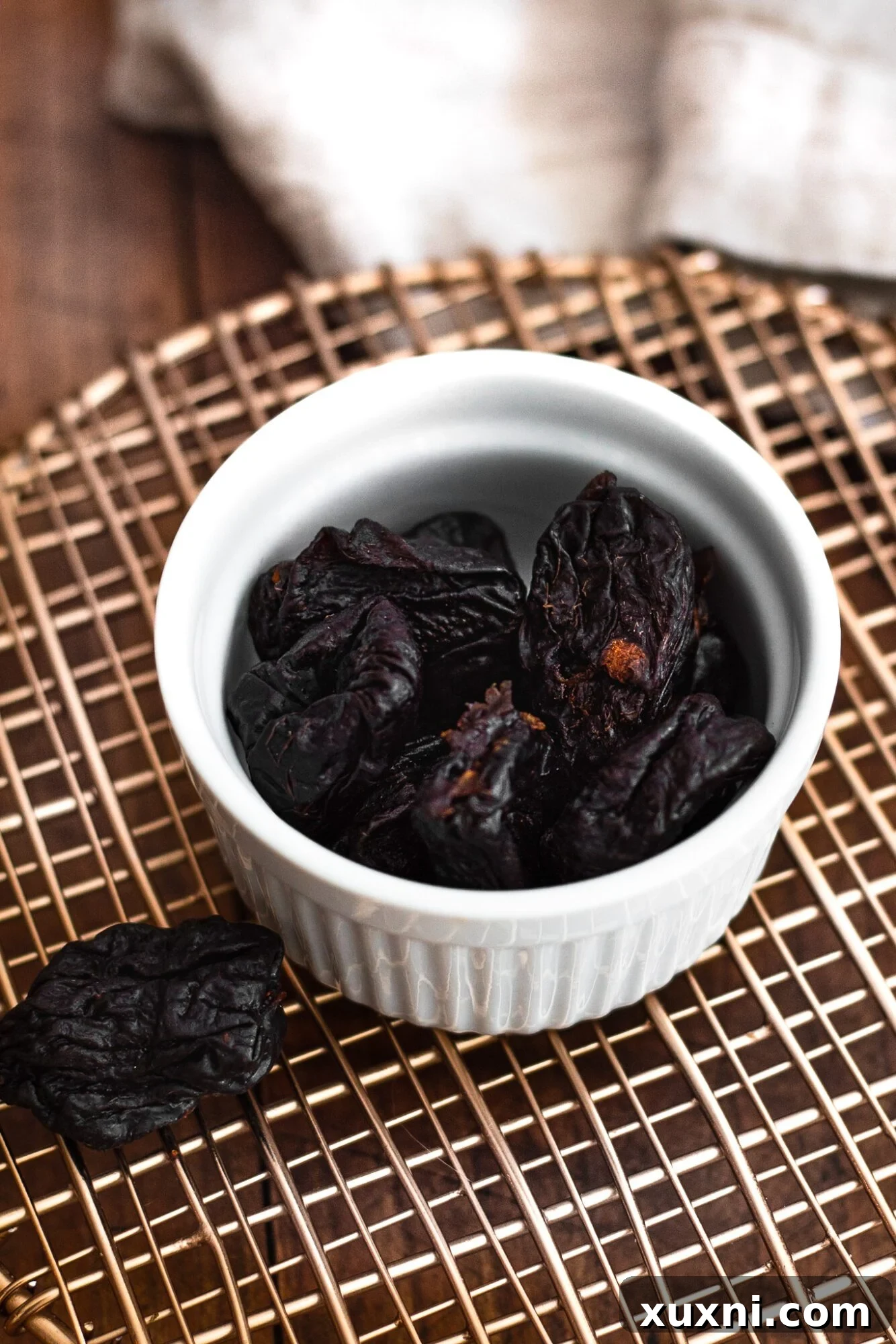 A rustic bowl filled with plump, dark California Prunes, showcasing their natural, rich texture and inviting appearance.