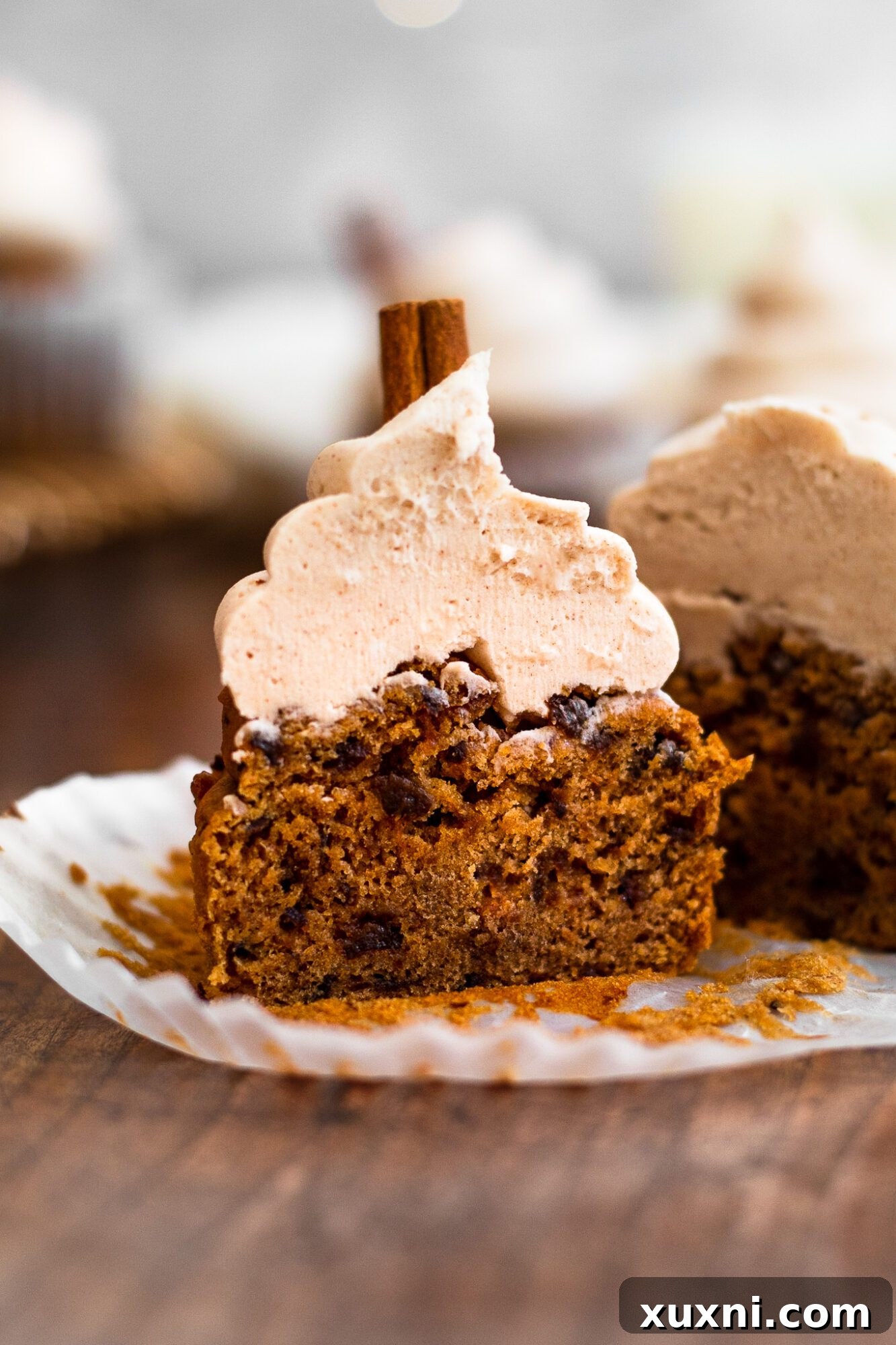 A vegan cinnamon cupcake cut in half, revealing its moist, light crumb texture and the creamy cinnamon buttercream frosting.