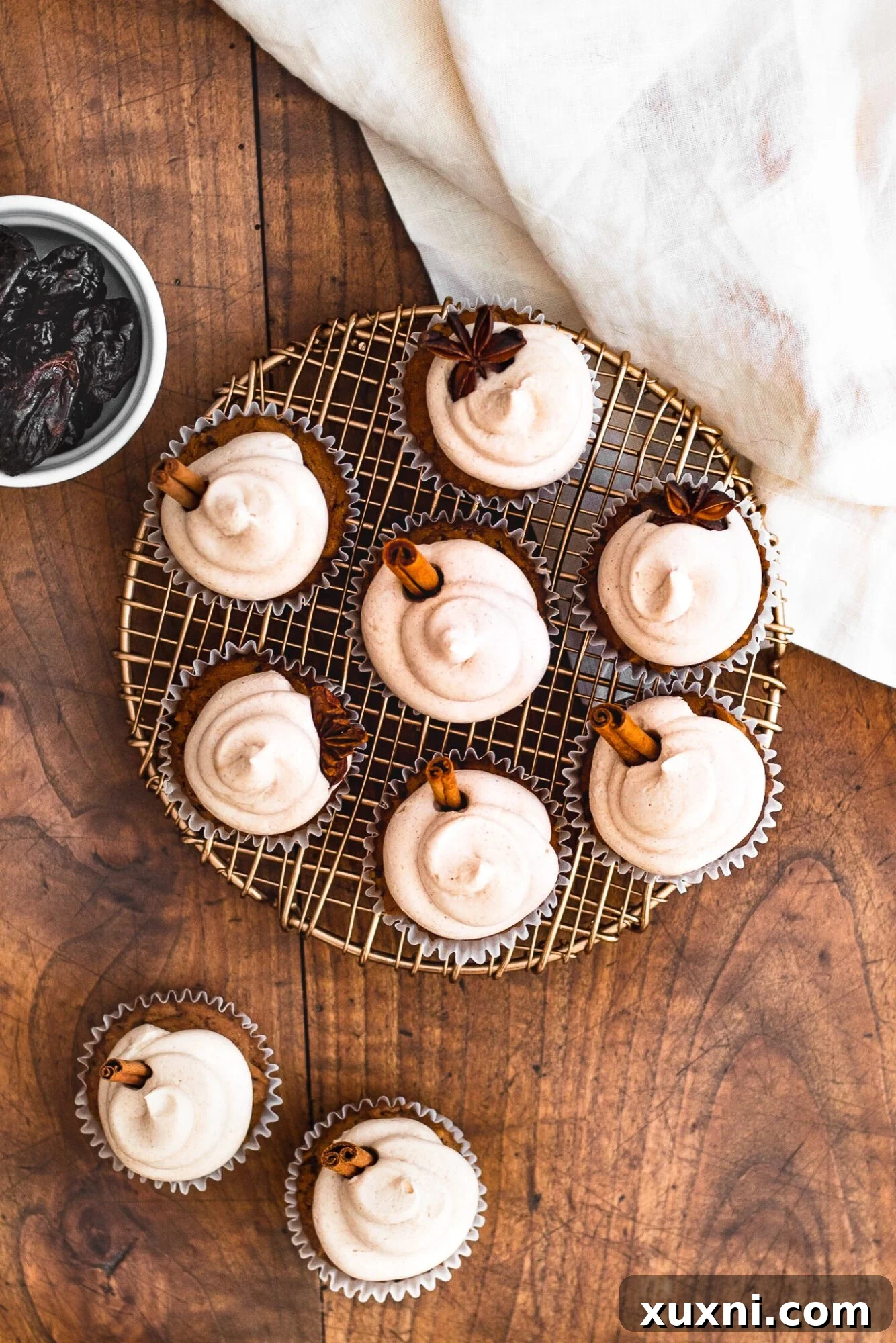 Overhead view of several cinnamon cupcakes arranged with California Prunes scattered around them, emphasizing the secret ingredient.