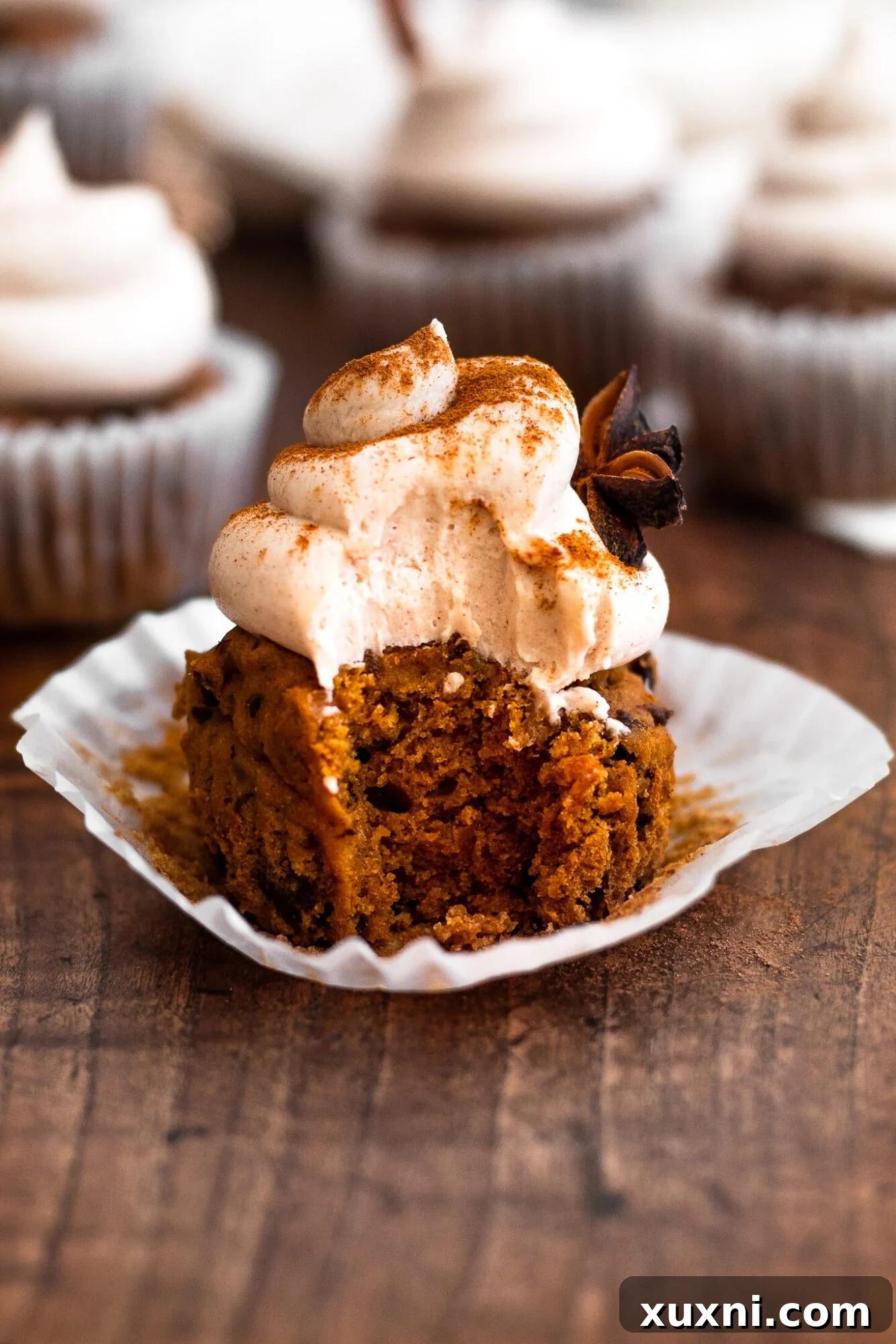 A vegan cinnamon cupcake with a bite taken out of it, revealing the fluffy interior and inviting texture.