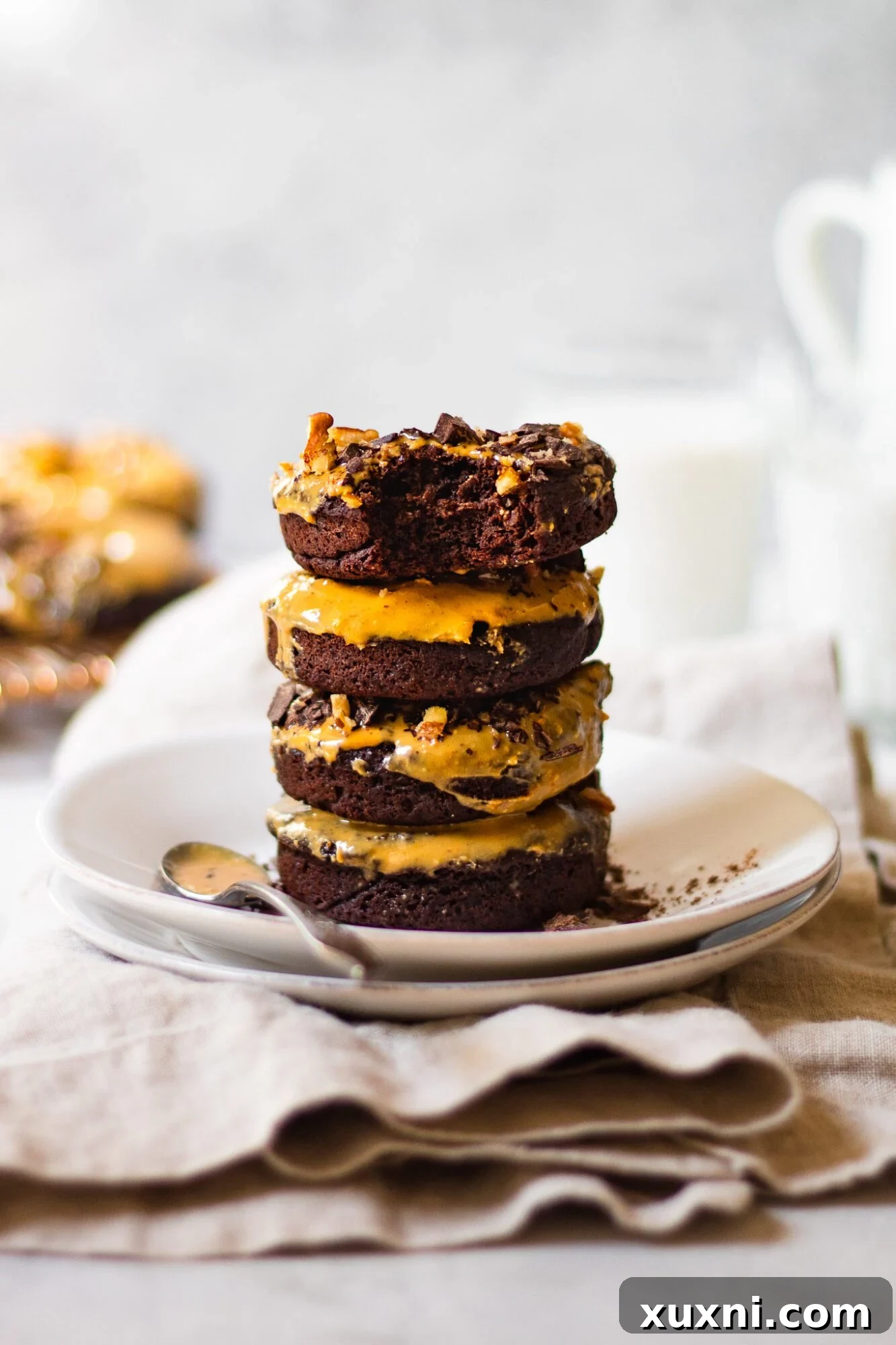 A stack of delicious chocolate donuts with a bite taken out of one