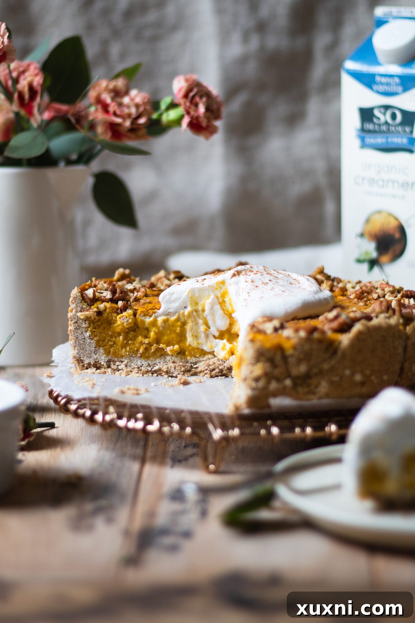 Sliced vegan pumpkin cheesecake with So Delicious creamer, showcasing its creamy texture.