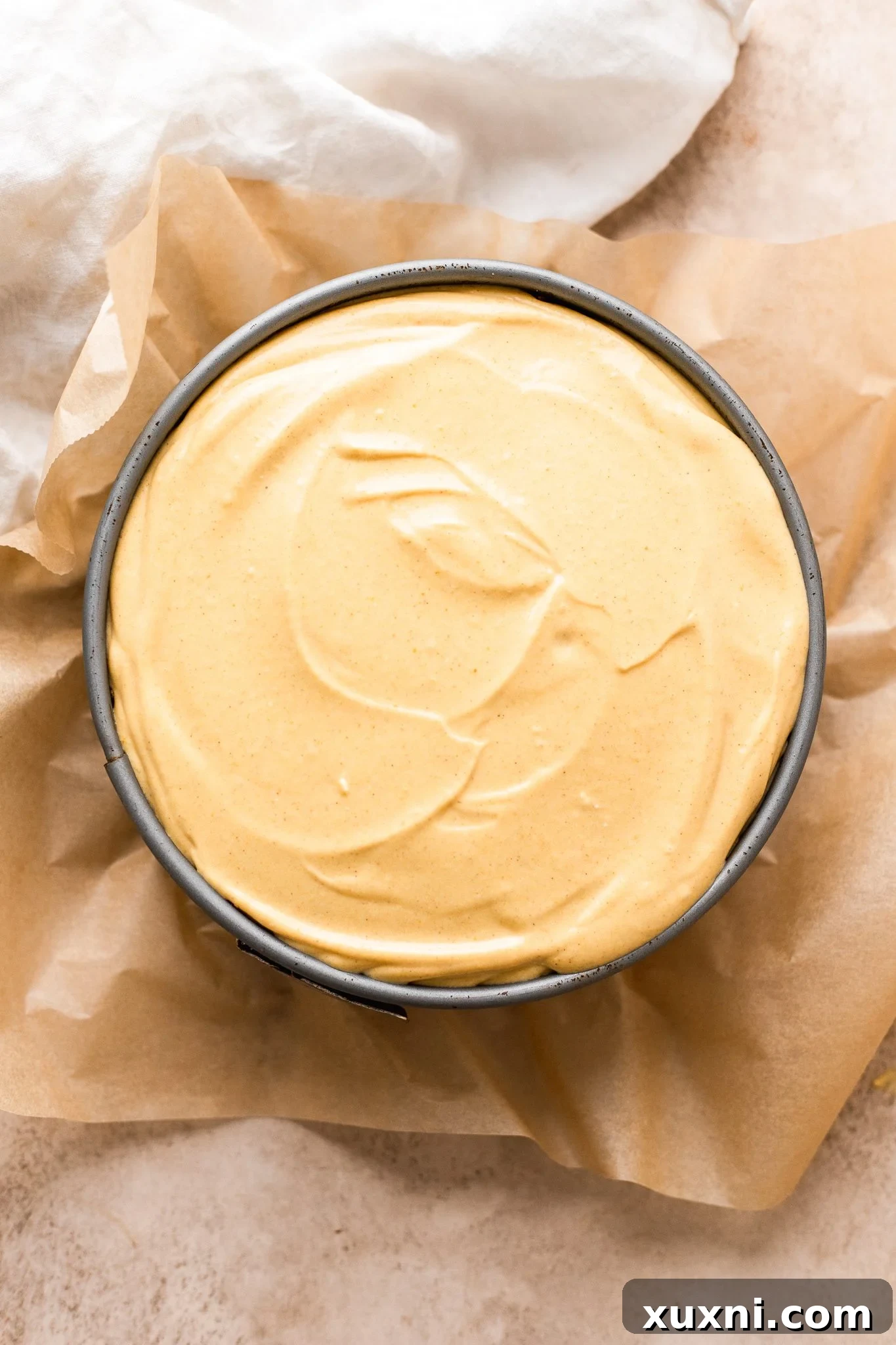 The creamy pumpkin cheesecake filling being poured into the prepared crust.