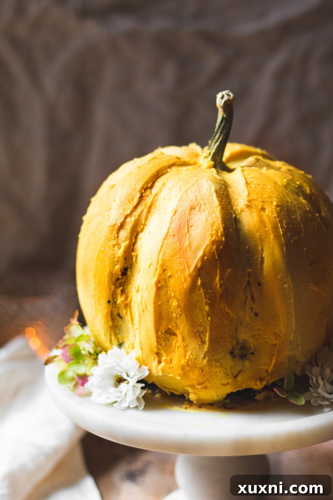 Close-up view of the intricately carved and frosted pumpkin cake, highlighting its rich chocolate interior and vibrant orange buttercream.