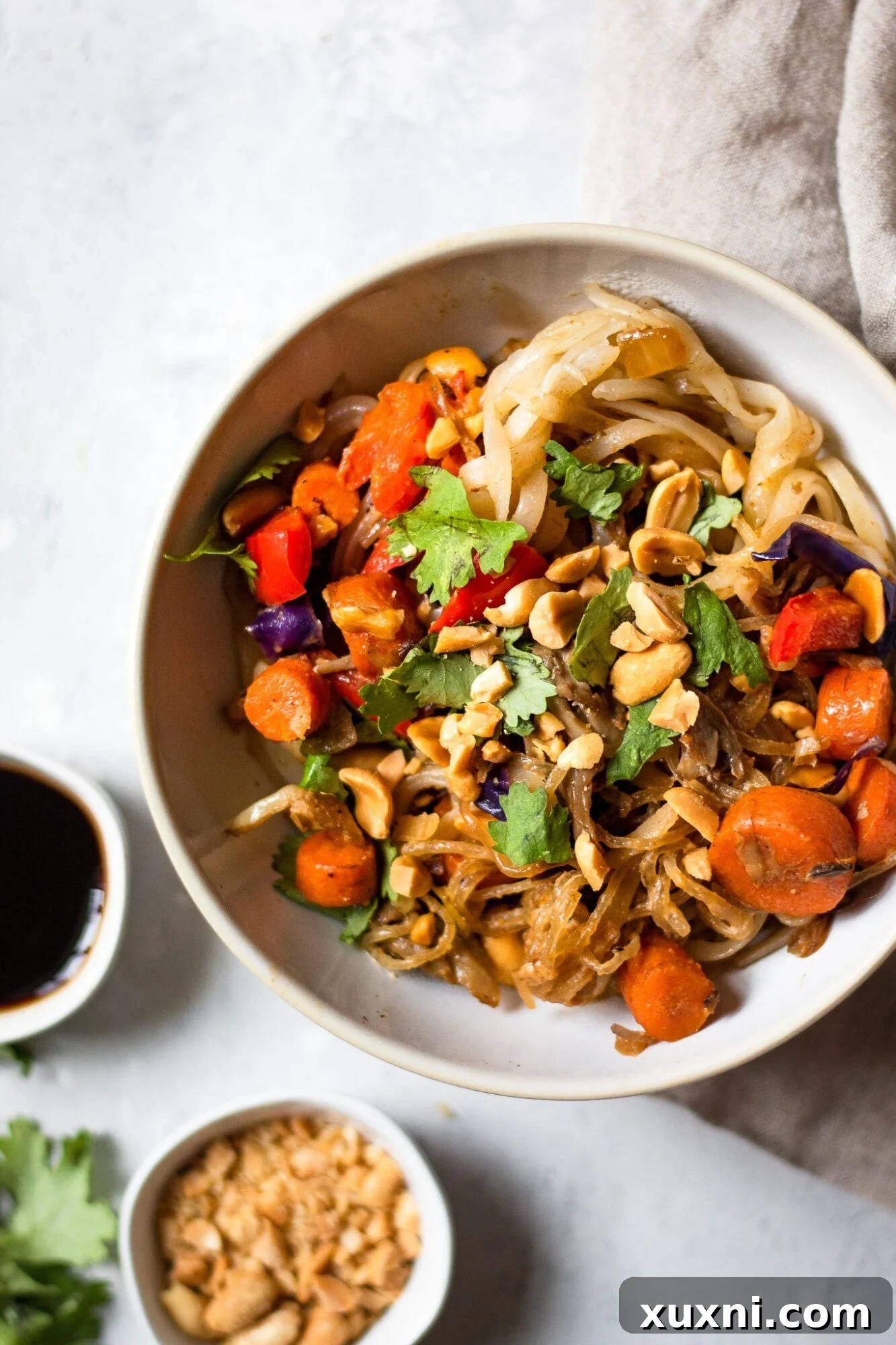 A serving of vegan Pad Thai in a bowl, garnished with peanuts and cilantro, viewed from above, ready to be enjoyed.