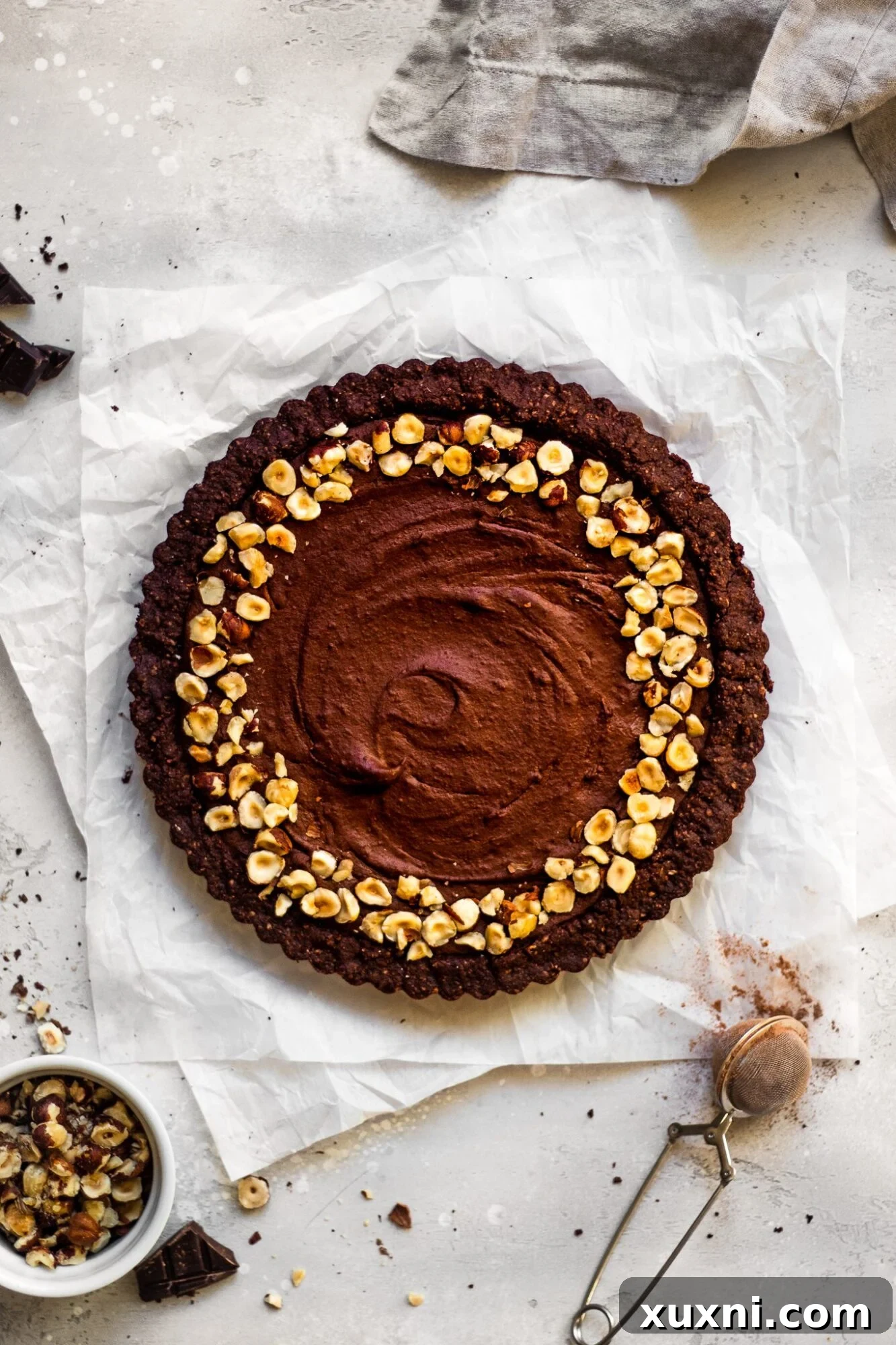 Vegan chocolate hazelnut tart on parchment paper, showcasing its rich texture and chocolate cookie crust