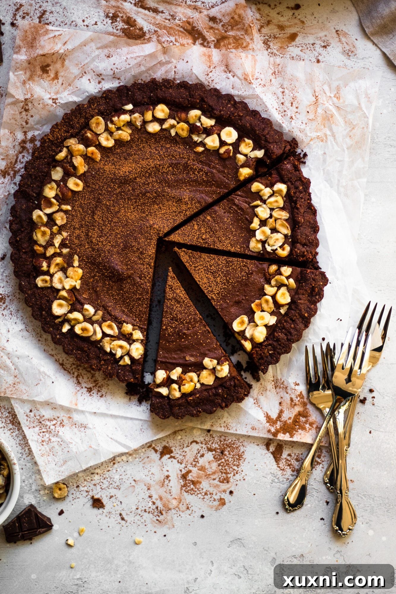 Close-up of perfectly sliced vegan chocolate hazelnut tart, revealing the thick, creamy filling and cookie-like crust