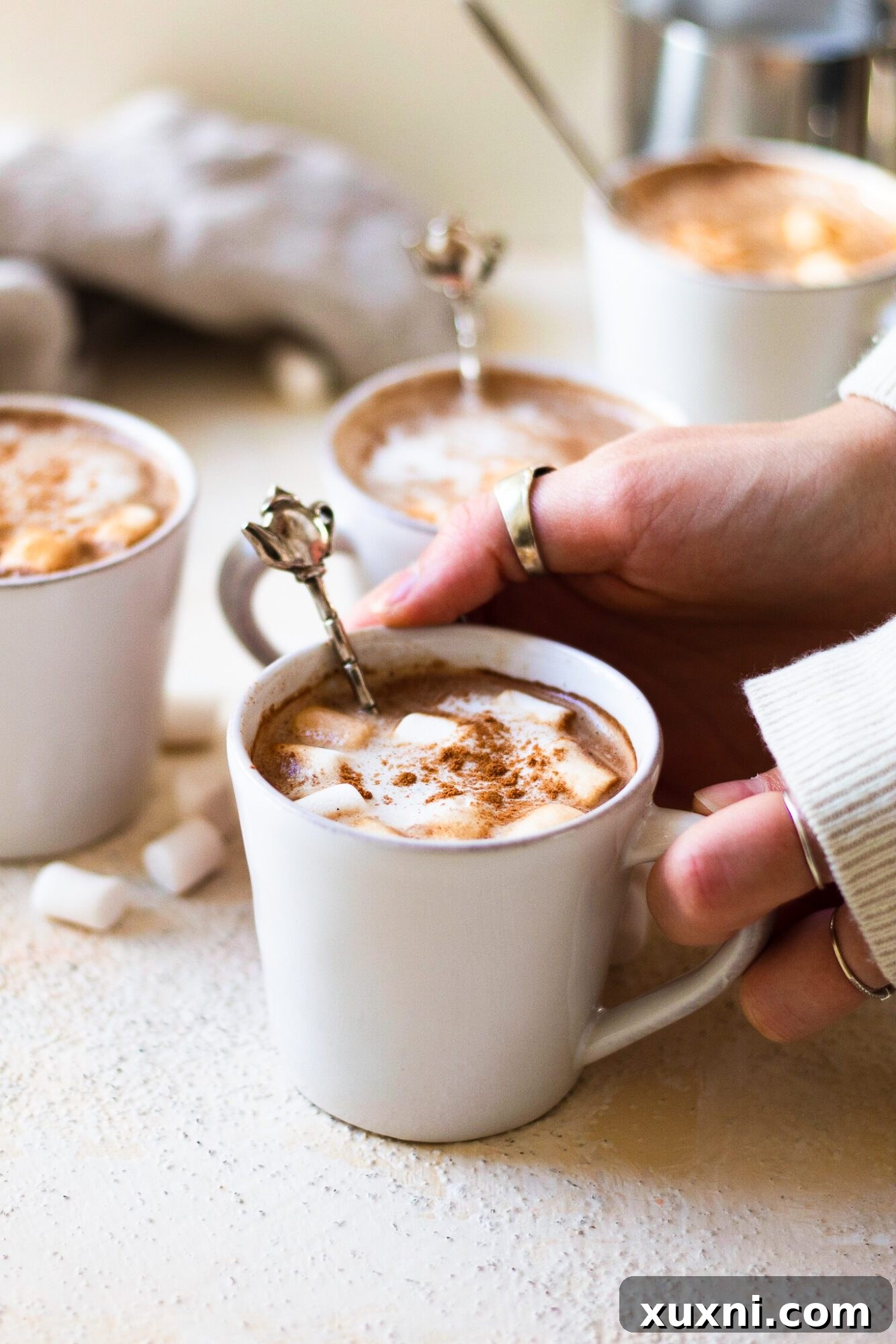 Hands holding a hot cocoa espresso drink with marshmallows