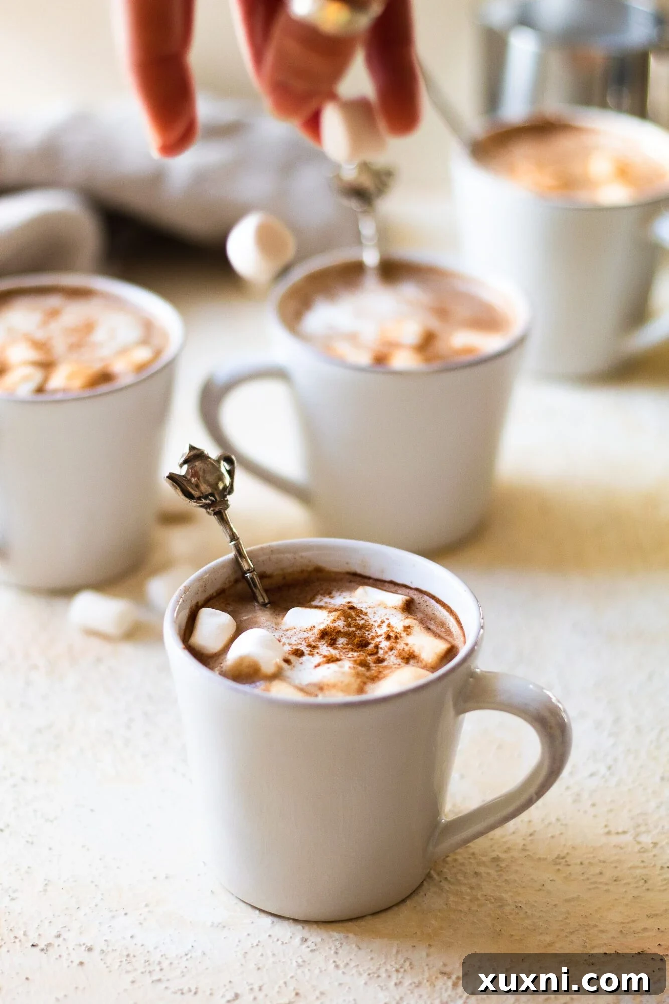 Hand dropping marshmallows into mugs of mocha latte