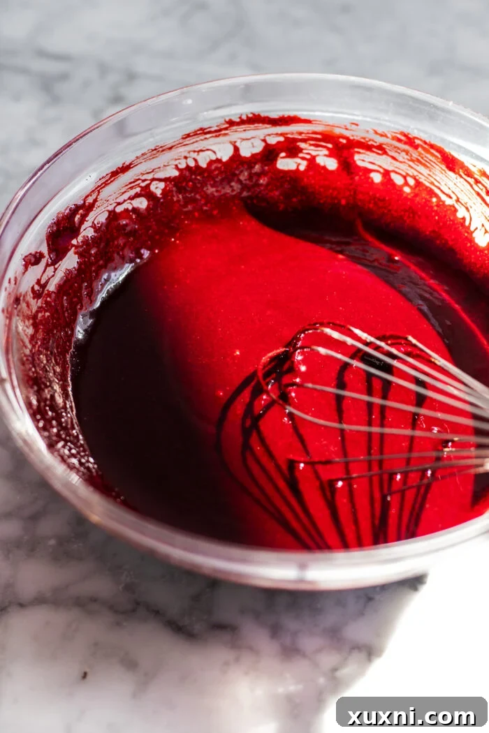 A bowl of red velvet cake batter being mixed, showing the vibrant color and smooth consistency.