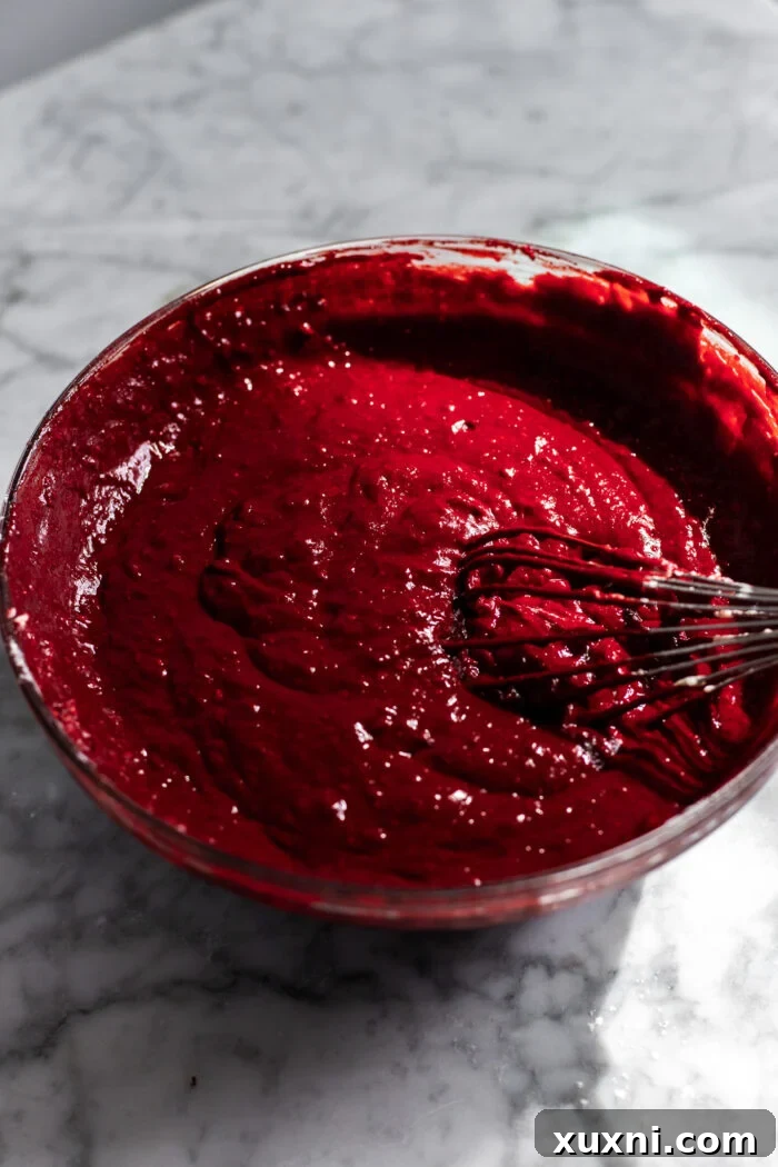 A bowl filled with vibrant red velvet cake batter, ready for baking.