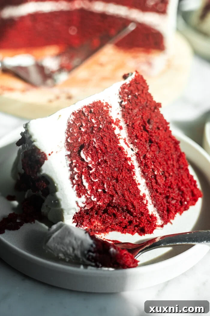 A close-up of a sliced and partially eaten red velvet cake, highlighting its moistness and layers of frosting.