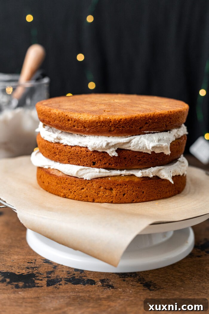 The process of frosting a layer cake with creamy vegan cream cheese frosting.