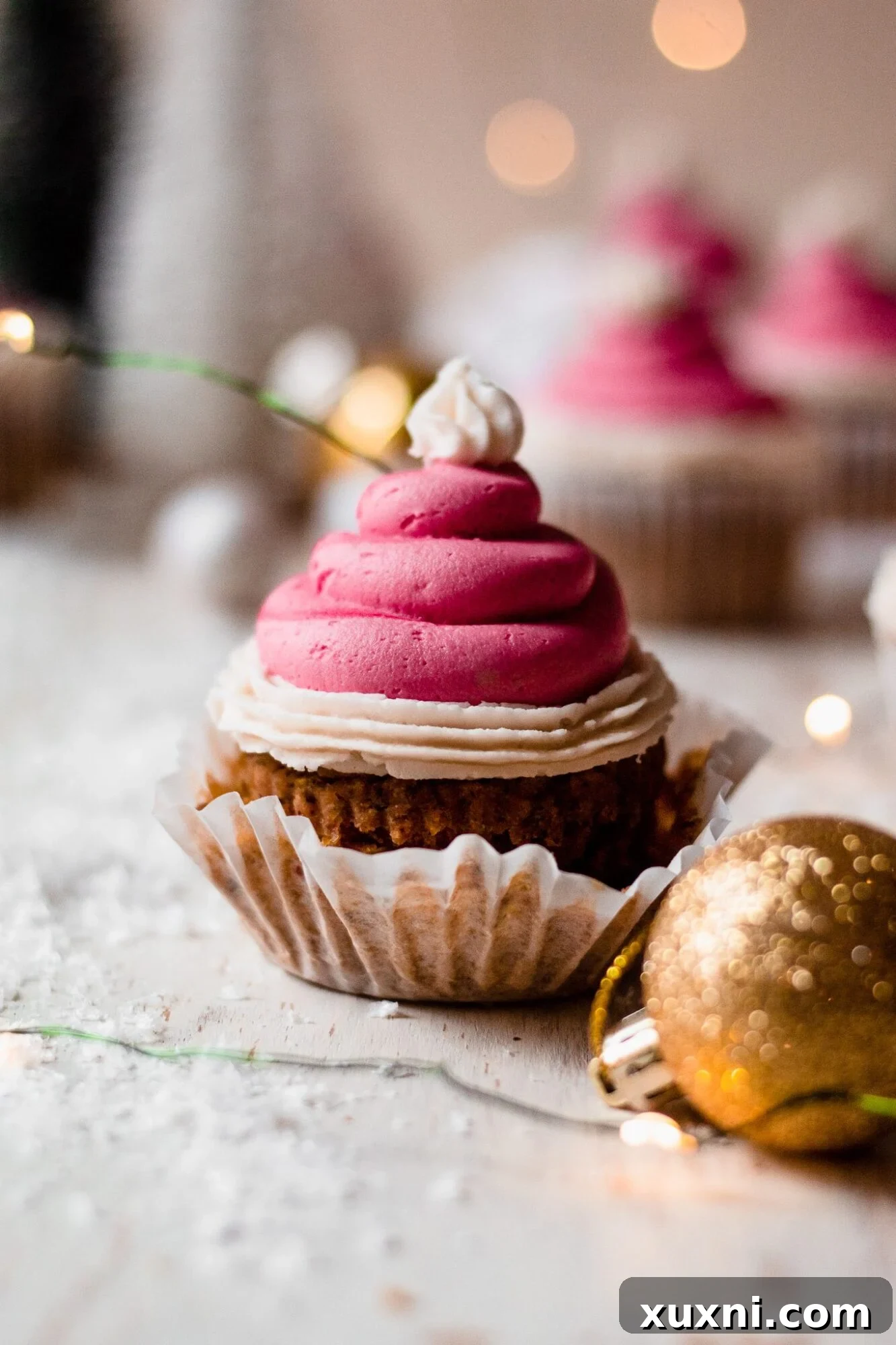 Festive Vegan Pistachio Santa Hat Cupcakes 2 A festive Grinch-themed pistachio cupcake with its liner peeled back, revealing the green cake and red Santa hat frosting.