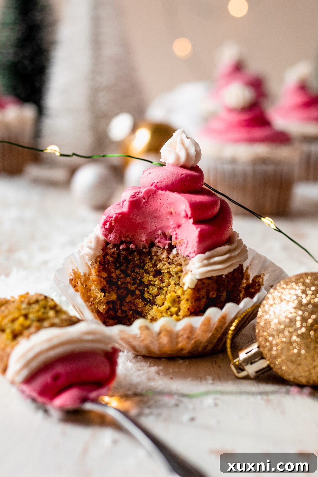 Festive Vegan Pistachio Santa Hat Cupcakes 12 A festive Christmas cupcake with a bite missing, showcasing the green pistachio cake and the distinct red and white Santa hat frosting.