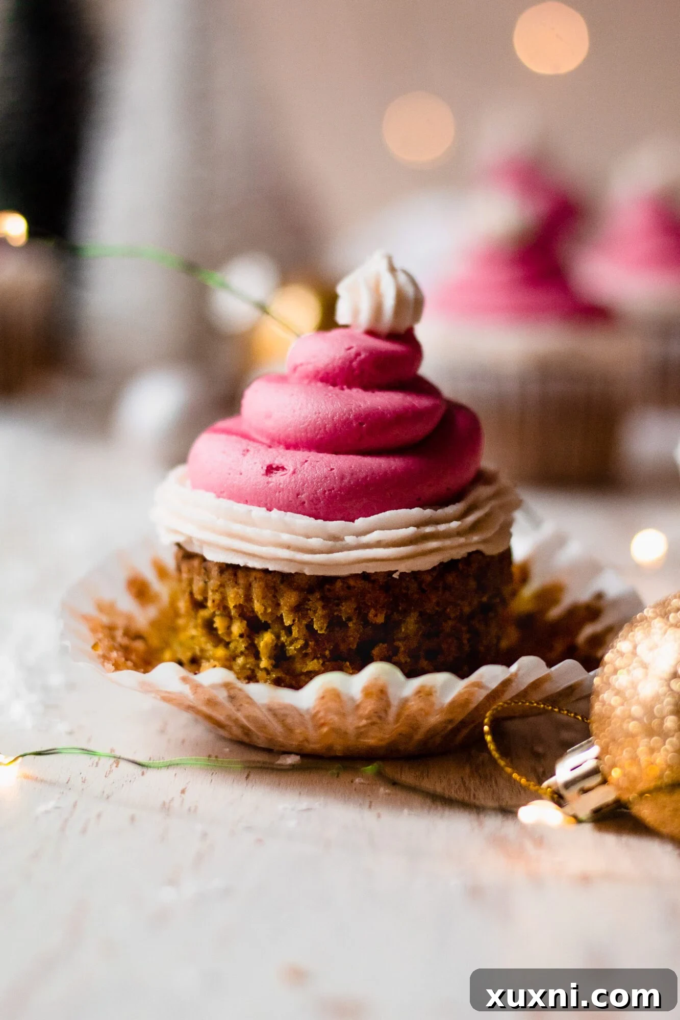 Festive Vegan Pistachio Santa Hat Cupcakes 7 A close-up of a vegan pistachio cupcake with its paper liner pulled down, highlighting the moist green cake and its appealing texture.