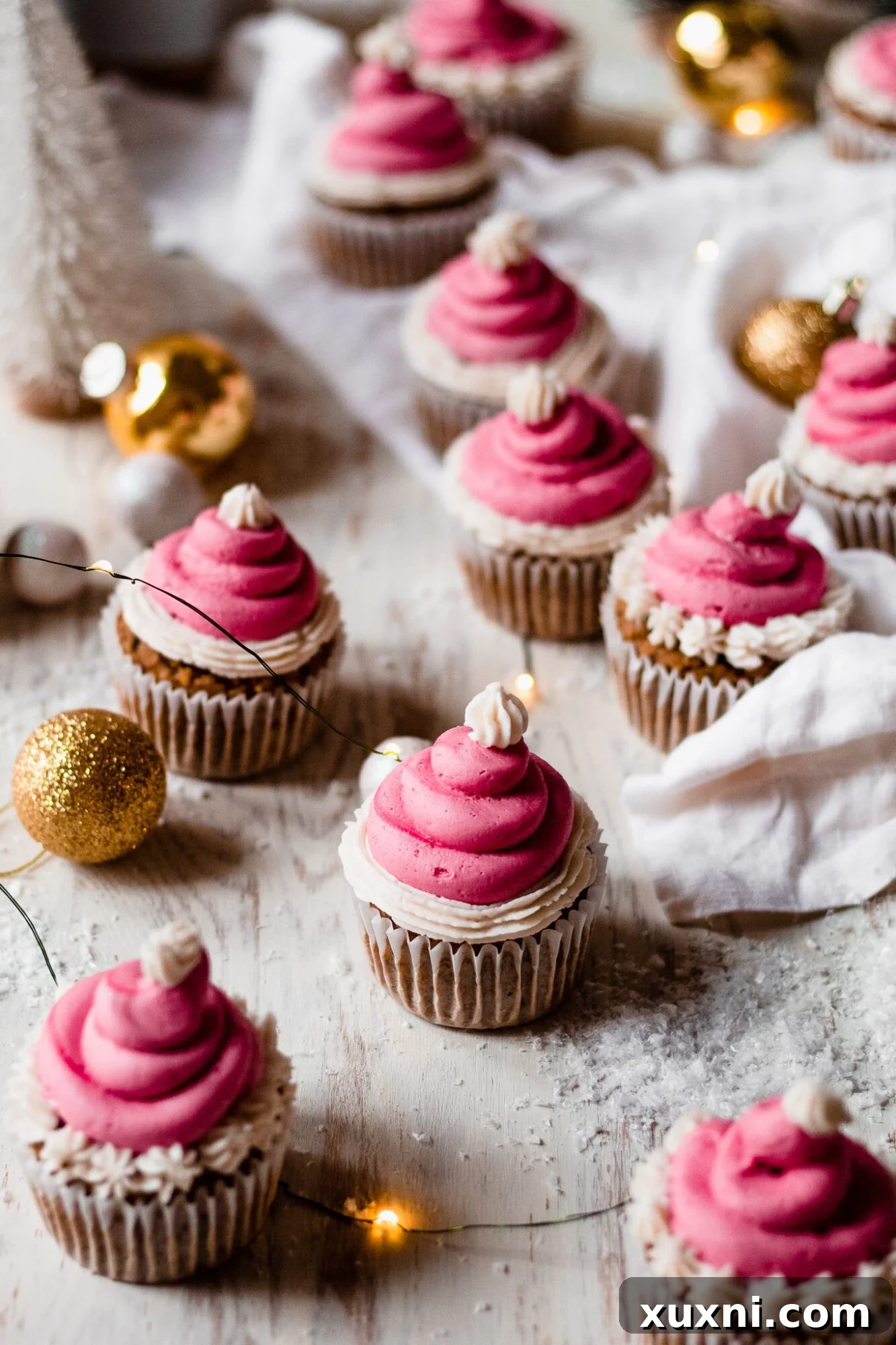Festive Vegan Pistachio Santa Hat Cupcakes 9 A horizontal view of several green pistachio cupcakes arranged in a line, featuring their red and white Santa hat frosting.