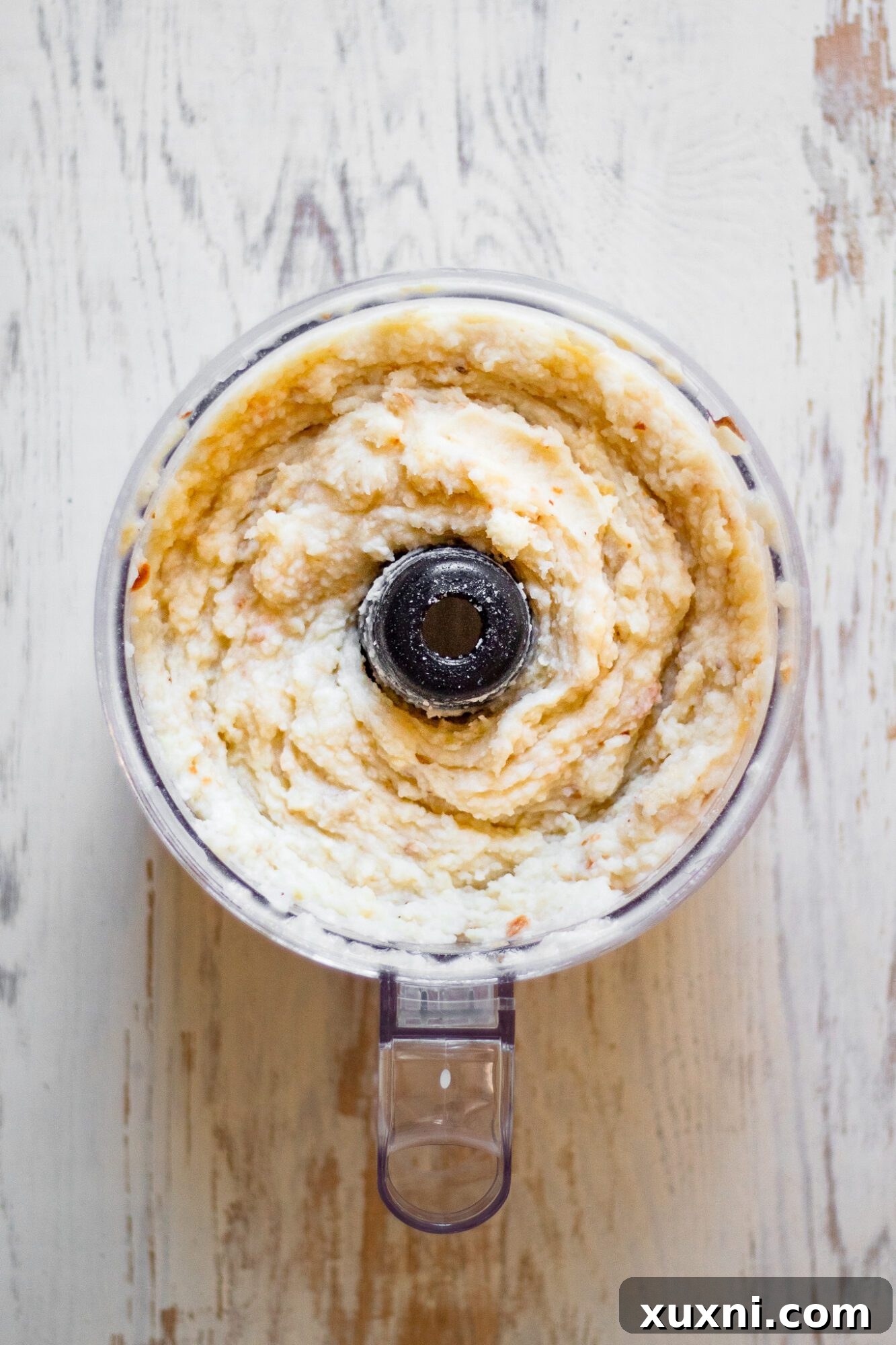 food processor blending potatoes with coconut milk and garlic