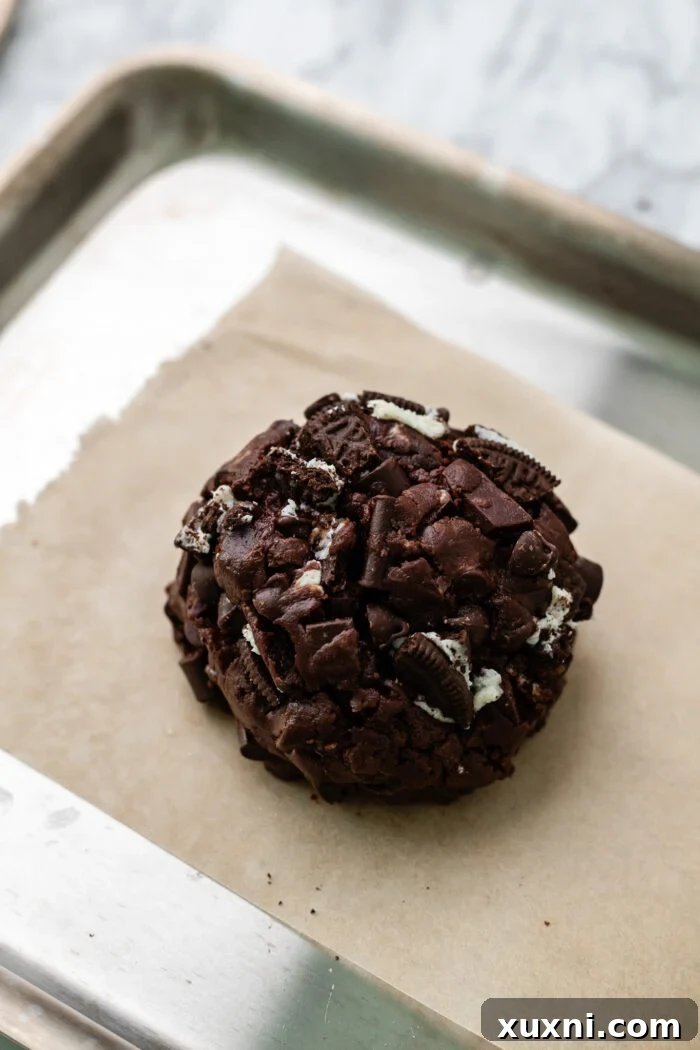 The cookie dough ball with a visible Nutella filling, placed on a baking sheet before baking.
