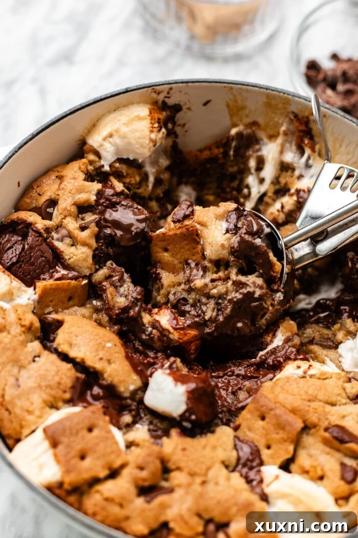 A hand scooping a serving of vegan s'mores cookie from the baking dish.