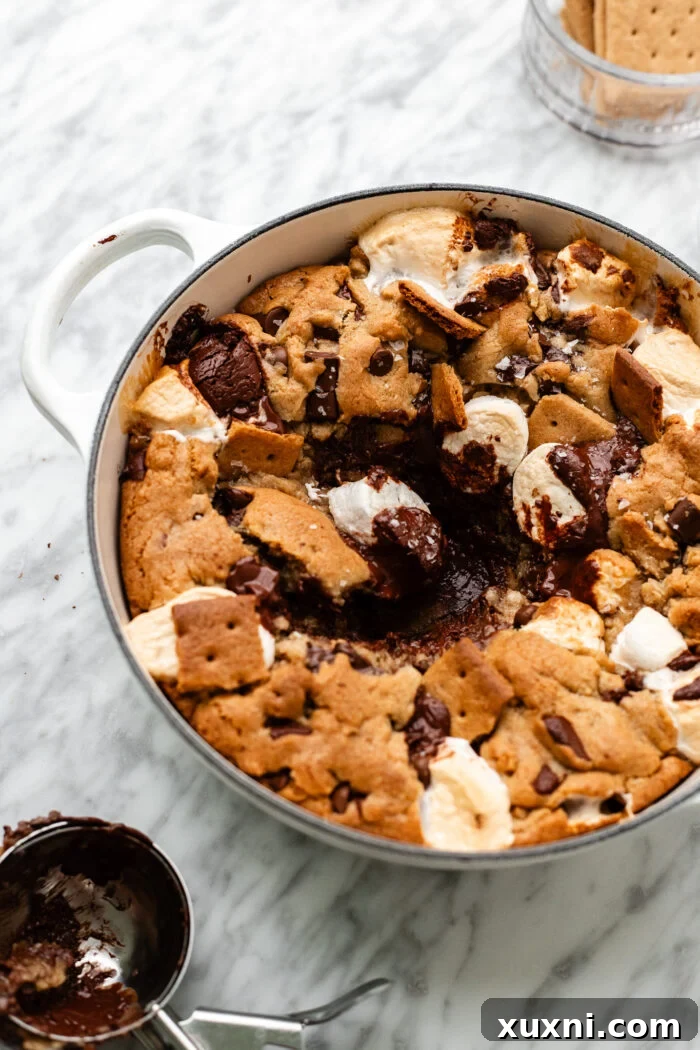 Close-up of a spoon scooping a portion of the warm, s'mores stuffed vegan cookie.