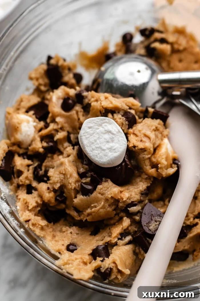 Filling individual portions of vegan cookie dough with s'mores ingredients.